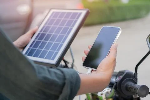 Back view of man connects solar panel to mobile phone for charge, eco-frien.. Stock Photos