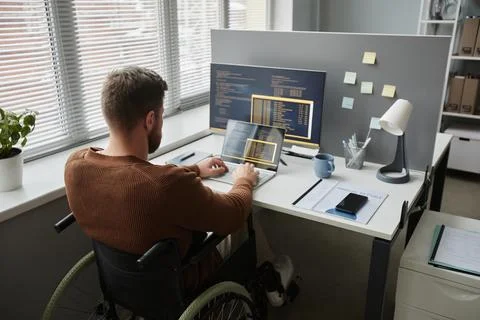 Back View Man with Disability Using Wheelchair and Coding in It Development 写真素材