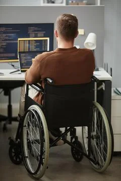 Back View Man with Disability Writing Code Working at Desk in Office Cubicle Foto stock