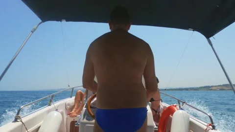 Back view of man driving fast motorboat with people sunbathing Stock Footage 278941283