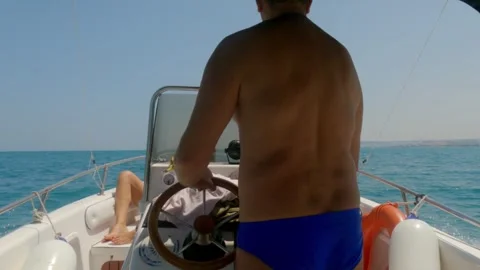 Back view of man driving fast motorboat with people sunbathing Видео 279869384