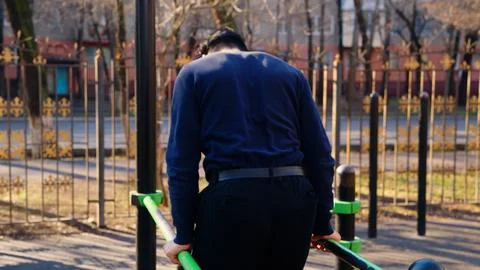 Back view of a man exercising on bars in the park Foto stock