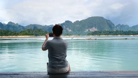 Back View of Man Filming Blog or Vlog on Mobile Phone at Amazing Lake Video stock 147677580
