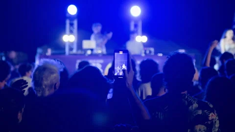 Back view man filming live night concert on smartphone with stage lights Stock Footage 320129909