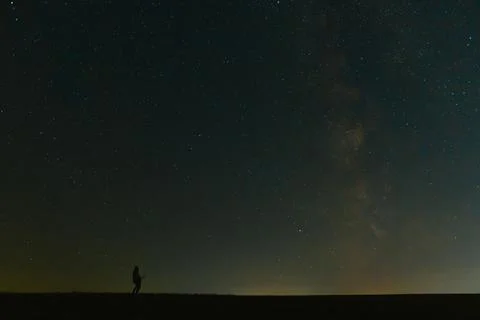 Back view of man with flashlight standing on green grassy field under beaut.. Foto stock