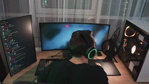 A back view of a man gamer wearing headphones is streaming online videogames Stock Footage 154451612