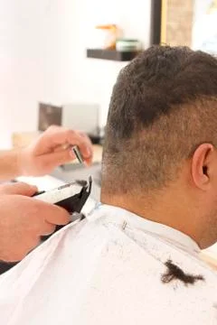 Back view of man getting short hair trimming at barber shop with clipper mach Stock Photos