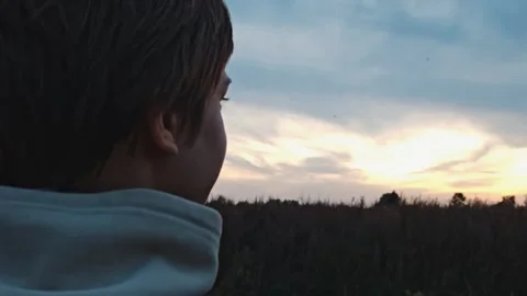 Back view. Man guy looks at the sunset. Young lonely guy walks at sunset. Stock Footage 317050470