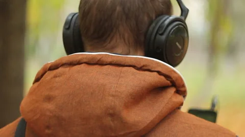 Back view of man with headphones holding mobile smart phone Vídeo Stock 68736504