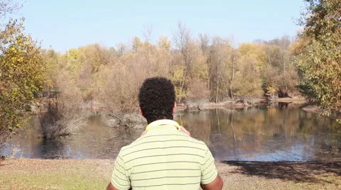 Back view of man with headphones listening to music by the lake Stock Footage 59555348