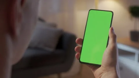 Back View of Man Holding Chroma Key Green Screen Smartphone Watching Content Stock Footage 170766374