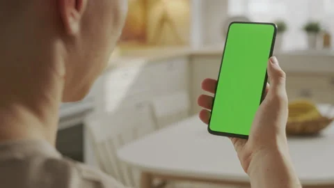 Back View of Man Holding Chroma Key Green Screen Smartphone Watching Content Stock Footage 205571977