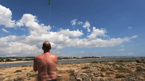 Back view of man holding kite on beach, slow-motion Stock Footage 279432793