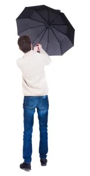 Back view of man in jeans under an umbrella. Standing young guy Stock Photos