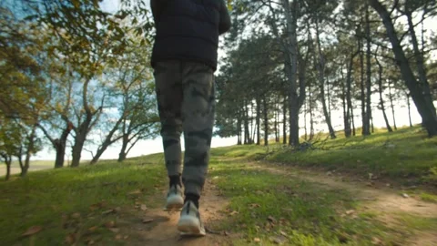 Back view of a man jogging through a tranquil forest path in camouflage pants. Stock-Footage 288673491