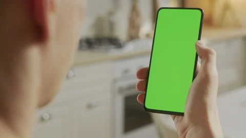 Back View of Man at Kitchen Room Sitting on a Chair Using Phone With Green Mock Stock Footage 171944866