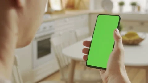 Back View of Man at Kitchen Room Sitting on a Chair Using Phone With Green Mock Stock Footage 205573232