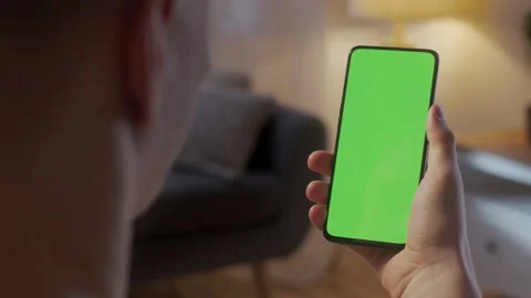 Back View of Man at Living Room Sitting on a Chair Using Phone With Green Mock Stock Footage 170928465