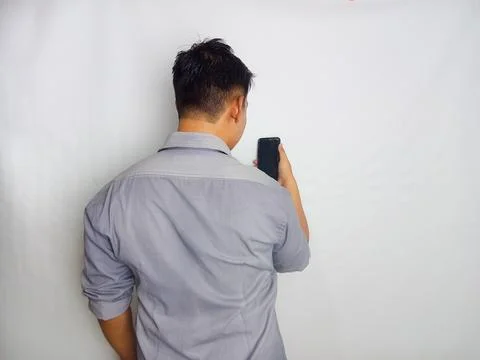 Back view of a man looking to the mobile phone that he hold Stock Photos