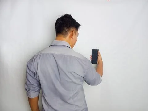 Back view of a man looking to the mobile phone that he hold Stock Photos