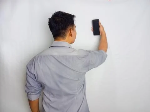 Back view of a man looking to the mobile phone that he hold Stock Photos