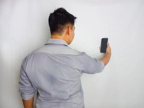 Back view of a man looking to the mobile phone that he hold Stock Photos