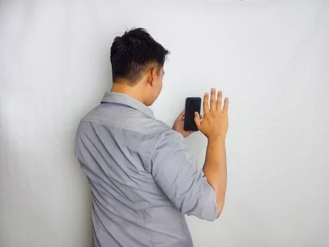 Back view of a man looking to the mobile phone that he hold Stock Photos