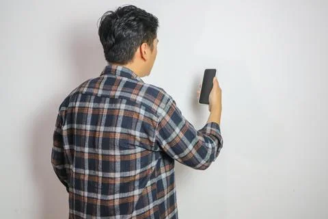 Back view of a man looking to the mobile phone that he hold Stock Photos