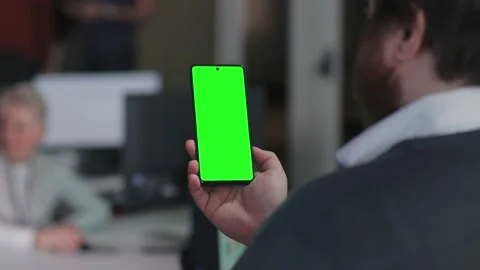 Back view of man looking at smartphone green screen in office Stock Footage 197564088