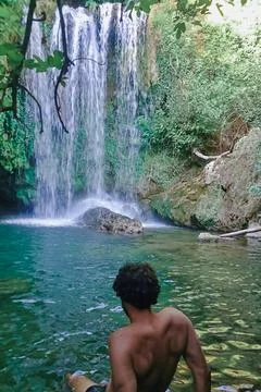 Back view of man looking at a waterfall in the mountains. Foto stock