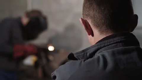 Back view of a man looking at welding without protective mask in a garage Stockbeeldmateriaal 143475711