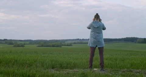 Back view of man observing something in binoculars standing on green field Stock Footage 135295601