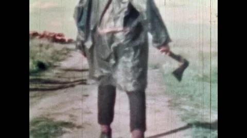 Back view, man in oilskin raincoat holding axe, waving dangerous weapon walking Stock Footage 281238513