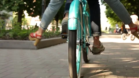 Back view of man pedalling a bike riding with woman on a seat or cargo rack. Low Stock Footage 136840690