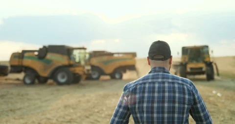 Back view on the man in the plaid blue shirt and hat walking in the field to the Stock-Footage 94449811