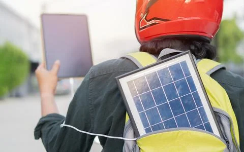 Back view of man with portable solar panel in backpack and tablet while sit.. Stock Photos