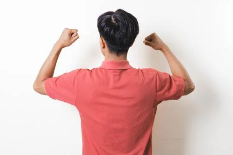 Back view of a man raising both fists in a confident pose, expressing stren.. Stock Photos