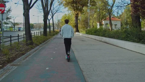 Back view of man rides an electric scooter in the city on a sunny day. Huma.. Stock Footage 236924297