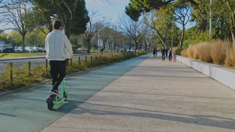 Back view of man rides an electric scooter in the city on a sunny day on bu.. Stock Footage 254660349