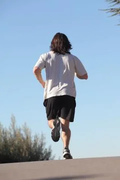 Back view of a man running on a road Stock Photos