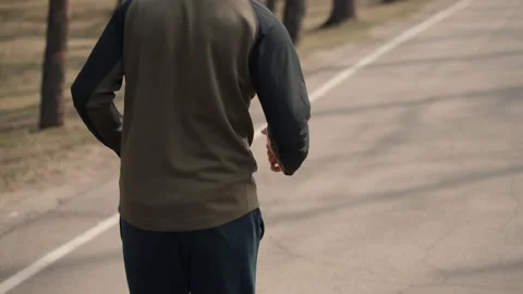 Back view man running in spring park. male jogger in tracksuit test his 스톡 동영상 133214205