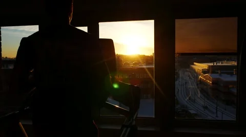 Back view of a man running on a treadmill near the window in rays of sunset Stock Footage 65530541
