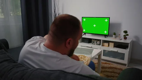Back view Man sitting on the couch in the living room Watching TV with Green Stock Footage 156343811