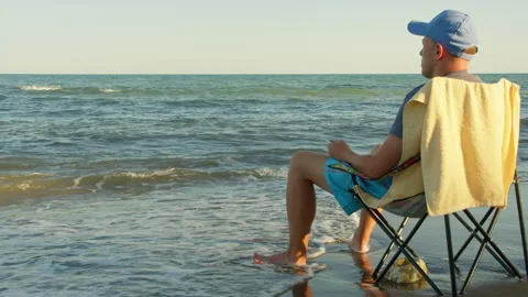 Back View of Man Sitting by the Sea at Sunset, Pebble Beach, Copy Space Stock Footage 333610690