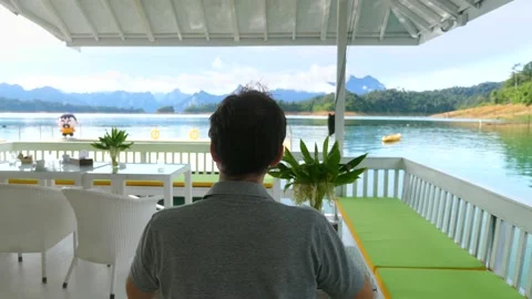 Back View of Man Sitting on Table with Outdoor Breakfast at Beautiful Blue Lake Stock Footage 141455450