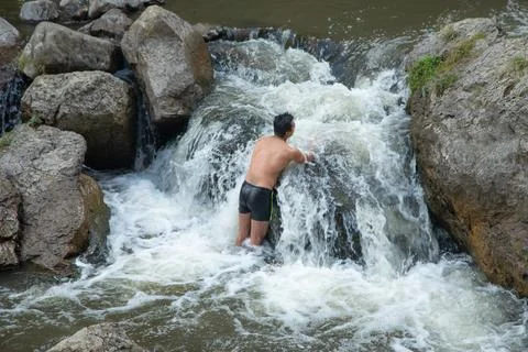 Back view of man in small waterfall. Stock Photos