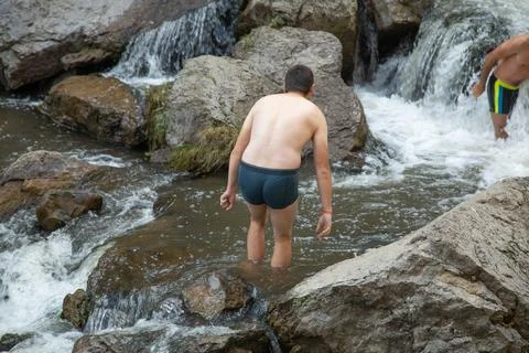 Back view of man in small waterfall. Stock Photos