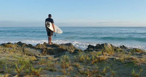 Back view man standing on beach with surfboard. Stock Footage 223045605