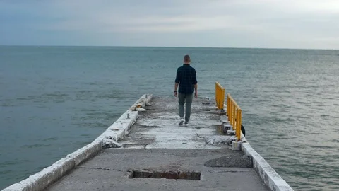 Back view of a man standing on the pier, enjoying sunset over sea. SLOW MO Stock Footage 97450215