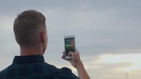 Back view of a man standing on the pier, enjoying sunset over sea and making Stock Footage 97450225